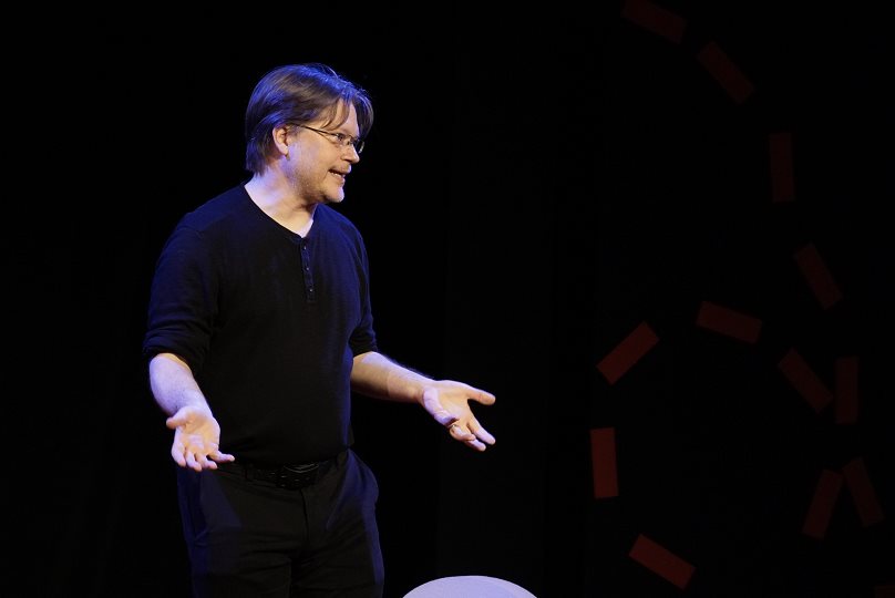 Tom Puketza speaking on a dark stage